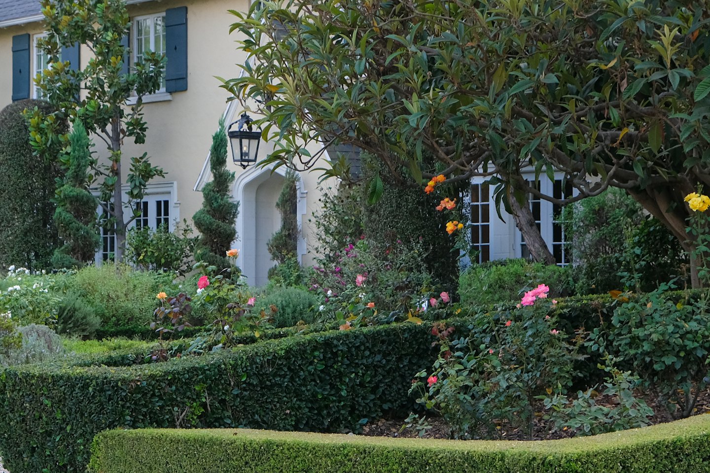 Rose colorate e siepi curate circondano una casa elegante.