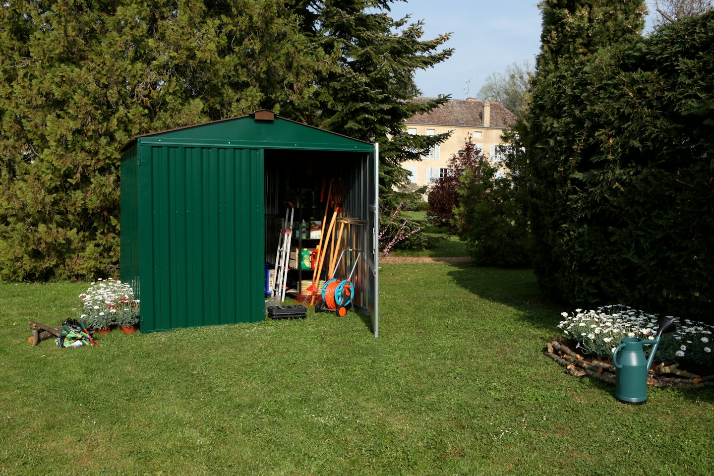 Una casetta da giardino su un prato con attrezzi riposti all'interno.