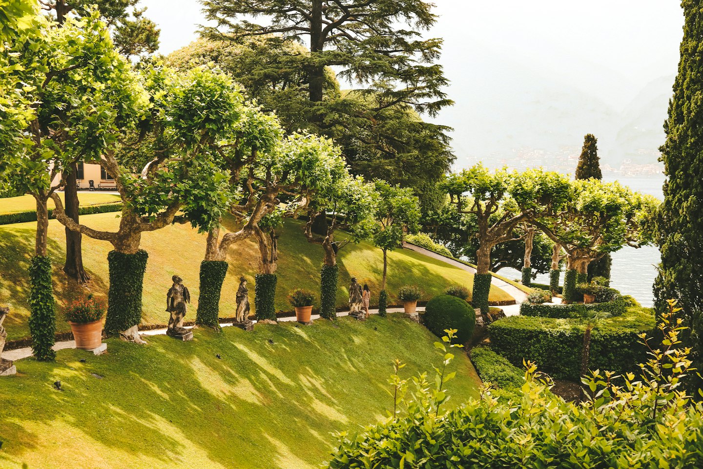 Un giardino a terrazze con alberi curati che conducono verso uno stagno.